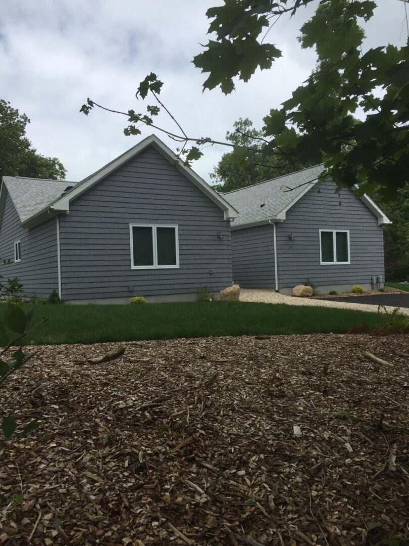 Two wooden houses in gray color side by side with trees all around