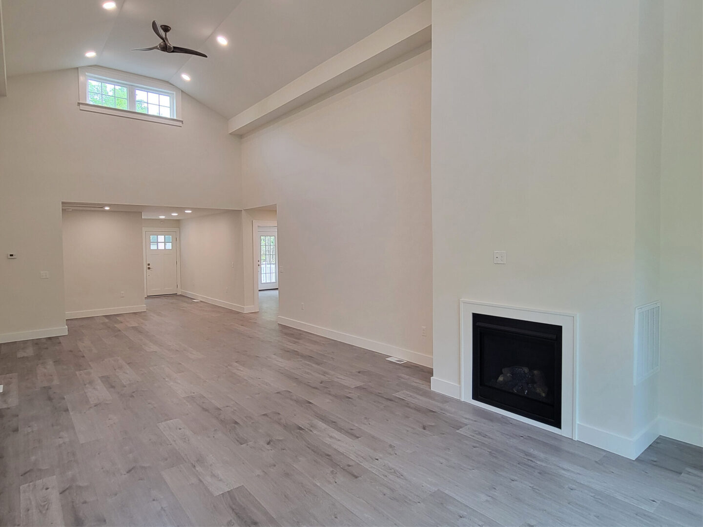 Spacious living room with high ceilings and fireplace.