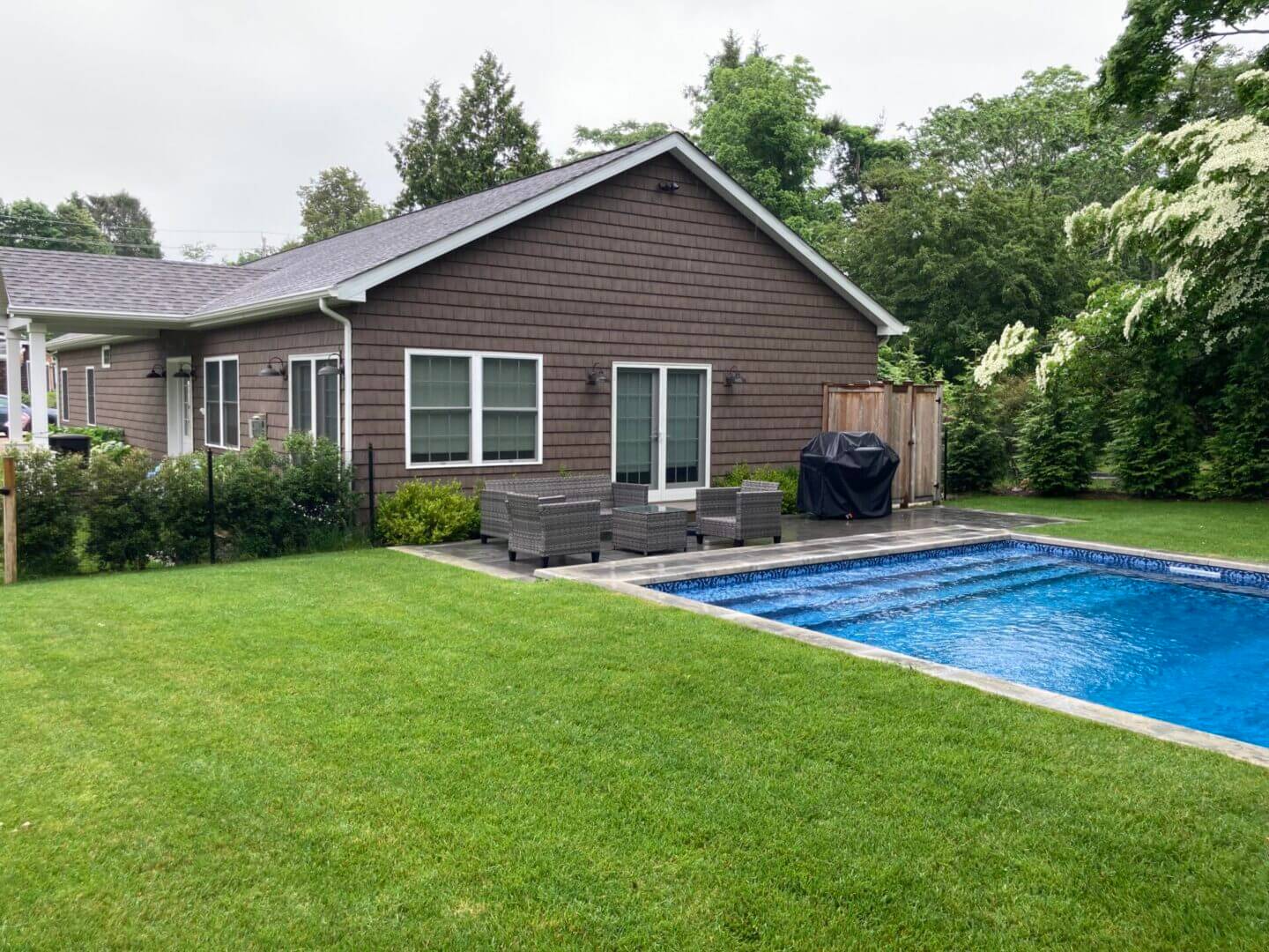 House with backyard pool and patio furniture.